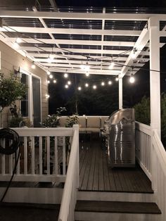 an outdoor patio covered in lights and string lights on the ceiling, next to a deck