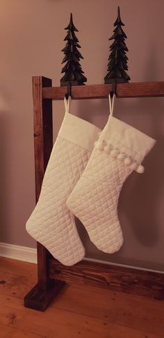 two white christmas stockings hanging from a wooden rail