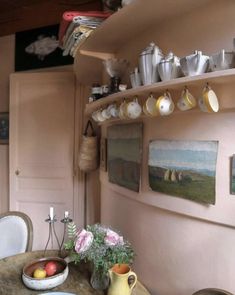 a table with plates, cups and bowls on it in front of a pink wall