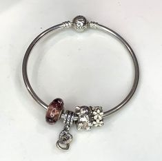 Authentic Pandora sterling bangle bracelet measuring 8".  Has 4 charms.  Has a screw on safety chain 1.  White floral charm 2.  elephant charm 3.  Hanging charm with interlocking hearts 4.  Purple glass bead with crytals Weight 22 gms Excellent condition   Before you buy, please reviews all photos because they are part of our description. All of the items are sold as, so naturally expect some minor imperfections. While preparing items for sale we carefully inspect each piece to make sure that yo Pandora Bracelet Bangle, Silver Adjustable Dangle Charm Bracelet, Pandora Bangle With Charms, Adjustable Bangle Charm Bracelet With Dangling Charms, Pandora Chain Bracelet, Silver Tarnish-resistant Metal Charm Bracelet, Pandora Bracelet Silver, Pandora Bangle Bracelet, Nickel-free Silver Bangle Charm Bracelet