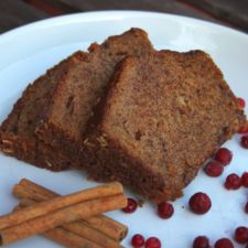 two pieces of bread on a plate with cinnamon sticks and cranberries next to it