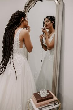 a woman in a wedding dress is looking at her reflection in the mirror and brushing her teeth