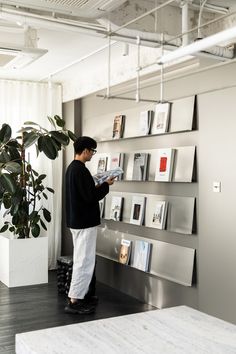 a man standing in front of a wall with pictures on it and holding a book