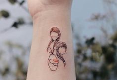 a woman's wrist tattoo with a drawing of a girl holding a baby in her arms