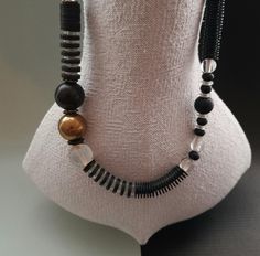 An elegant long necklace asymmetrically designed with ebony-glass and brass beads from Mali. Ebony and bakelite -heishi are integrated in this necklace. The necklace closes with a convenient magnetic clast. Size of brass bead: 21 mm Length : 56 cm or 22,04 " inch Weight : 100 gramm Elegant Black Beaded Necklace With Wooden Beads, Elegant Black Necklace With Wooden Beads, Elegant Black Wooden Beads, Hand-strung Black Necklaces With Round Beads, Adjustable Black Hand-strung Beaded Necklaces, Formal Black Multi-strand Beaded Necklaces, Artisan Black Beaded Hand-strung Necklace, Elegant Black Multi-strand Beaded Necklaces, Bakelite Necklace