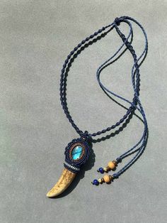 a long necklace with a blue beaded pendant and an animal's tooth