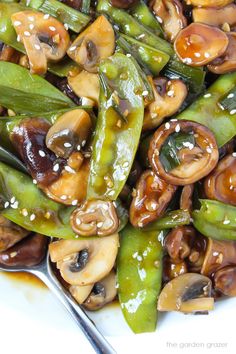 stir fried mushrooms and green beans with sesame seeds on a white plate, ready to be eaten