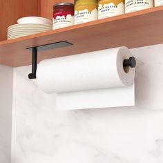 two rolls of toilet paper are hanging on the wall above a shelf with jars and cups