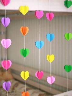 colorful paper hearts hanging from strings on a bed