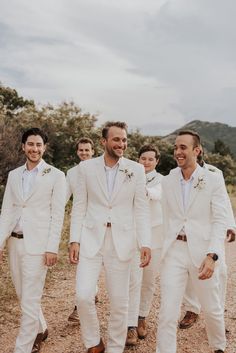 a group of men in white suits standing next to each other on a dirt road