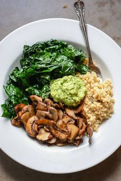 a white plate topped with mushrooms, rice and spinach