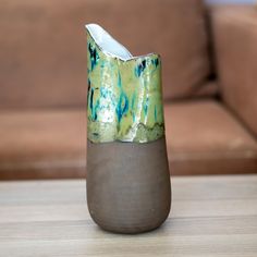 a vase sitting on top of a wooden table next to a brown couch in a living room