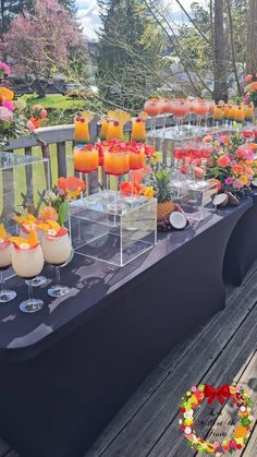 a long table is set up with drinks and flowers on it for an outdoor party