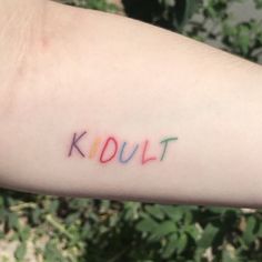 a person's arm with the word kdult written on it in multicolored ink