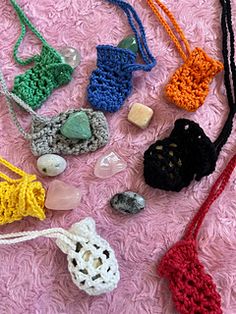 several crocheted items are laid out on a pink surface, including necklaces and beads