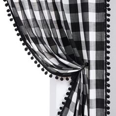 a black and white checkered curtain with pom poms