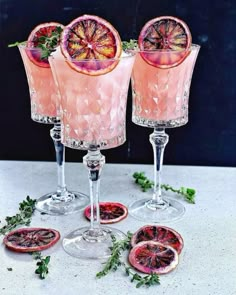 three glasses filled with pink liquid and garnished with grapefruit