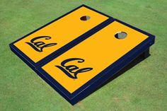 a yellow and blue cornhole board on the ground with an ear hole in it