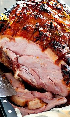 sliced ham sitting on top of a pan covered in bbq sauce and garnished with herbs