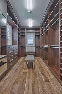 an empty walk in closet with wooden flooring and built - in shelving units