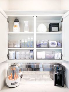 a kitchen with white cupboards filled with lots of clutter and containers on top of them