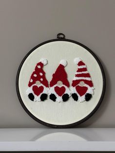 a white wall hanging with three red and white christmas hats on it's sides