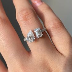 a woman's hand with two engagement rings on top of her finger and the other ring