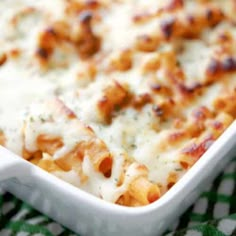 a casserole dish with cheese and meat in it sitting on a checkered cloth