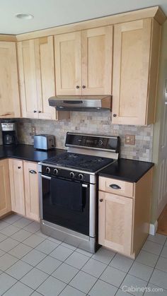 an empty kitchen with stainless steel appliances and wood cabinetry on the walls, tile flooring