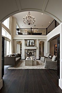 a living room filled with lots of furniture and a chandelier above the fireplace