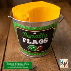 a bucket filled with yellow napkins sitting on top of a wooden table next to a football field