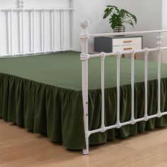 a bed with green bedspread and white rails