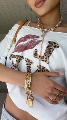 a close up of a person wearing a white shirt and leopard print bracelet with gold rings