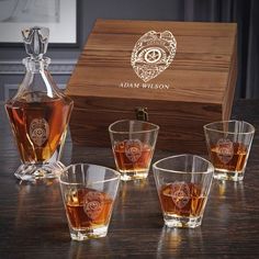 four glasses and a decanter sitting on a table next to a wooden box