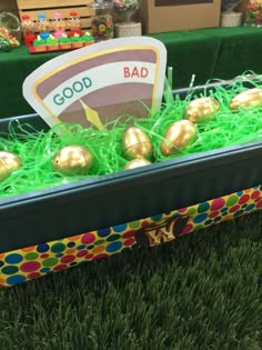 an easter basket filled with gold eggs and green grass in front of a table full of candy