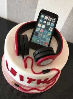 a cell phone and headphones on top of a white cake with red icing