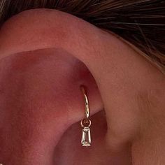 a woman's ear is shown with a gold cartilage and diamond earrings