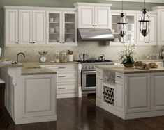 a kitchen with white cabinets and wood floors is pictured in this image, there are two chandeliers hanging from the ceiling