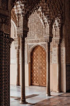 an intricately decorated building with columns and wooden doors in the middle of it's courtyard