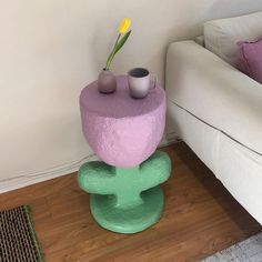 two vases are sitting on top of a small table in front of a couch