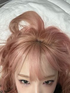 a doll with pink hair laying on top of a bed