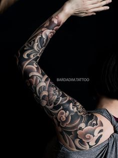 a woman with tattoos on her arm and arms is holding out her hand to the side