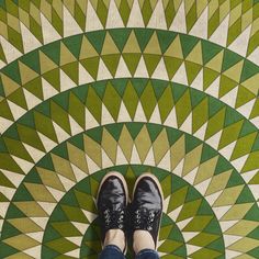 a person standing in front of a green and white floor with geometric designs on it