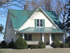 a white house with green roof and trees