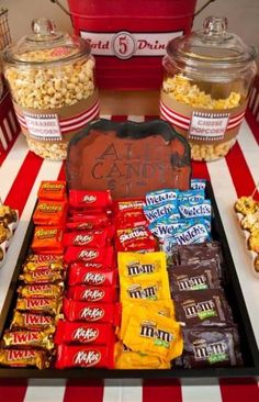 an assortment of candy and candies on a table in front of popcorn buckets