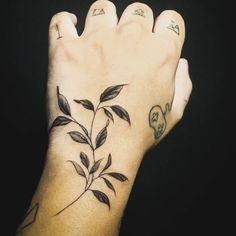 a person's hand with tattoos on it and a plant growing out of the palm