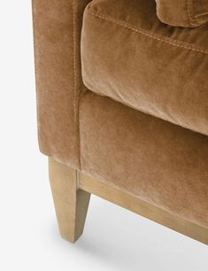 the back end of a brown couch with wooden legs