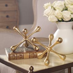 a table topped with white roses next to a vase filled with gold crossbones