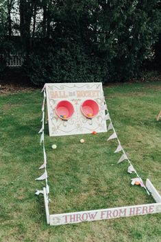 two red bowls sitting on top of a grass covered field next to a sign that says throw frisbees