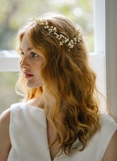 a woman with red hair wearing a white dress and a headpiece made of flowers